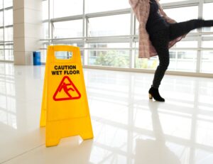 A woman slipping next to a wet floor sign.