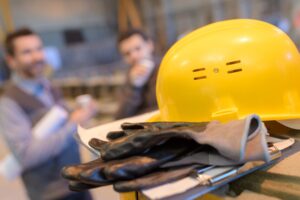 A yellow hardhat and gloves sit on a workbench