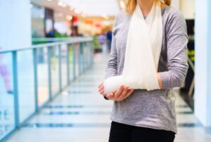A woman with her arm in a sling inside a shopping centre.