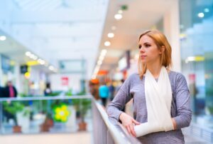 A woman with her arm in a sling stands in a shopping centre.