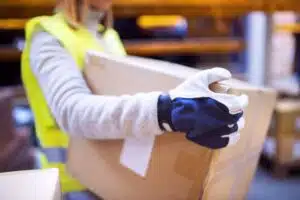 A close up image of someone carrying a box wearing protective gloves.