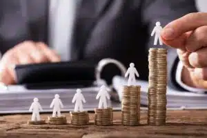 Paper figures of people standing on top different piles of coins