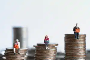 Three piles of copper coins in ascending order with figures of miniature people sitting on top