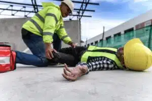 A worker moves another worker's leg checking for hip or pelvis injuries. 
