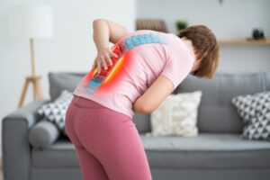 A woman hunched over holding her back in pain due to nerve damage.